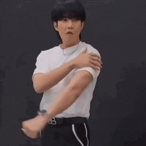 a man in a white shirt is flexing his muscles while wearing a watch .