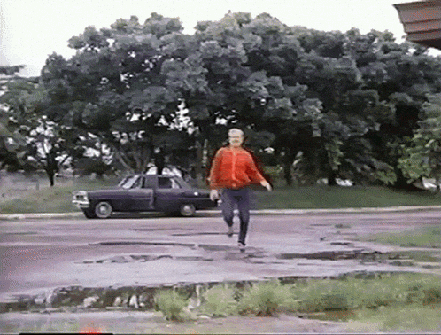 a woman in a red jacket is running down the street