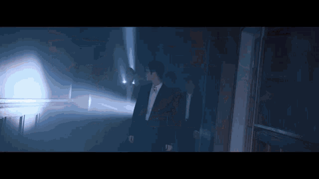 a man in a suit and tie is standing in a dark room