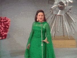 a woman singing into a microphone in a green dress