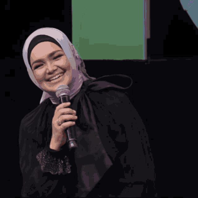 a woman speaking into a microphone in front of a sign that says " melete "