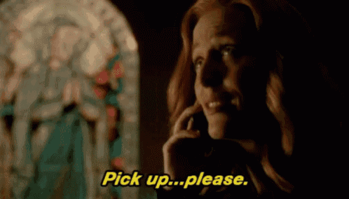 a woman is talking on a cell phone in front of a stained glass window and saying pick up please .