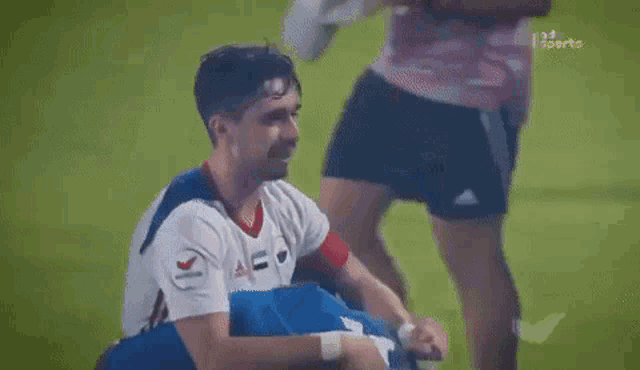 a couple of soccer players are hugging each other on the field .