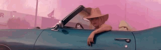 a woman in a cowboy hat is sitting in a convertible car .