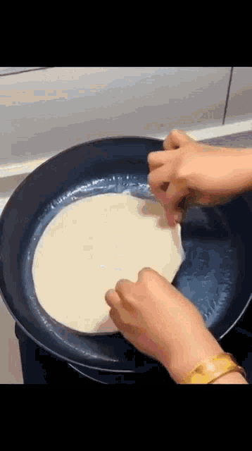 a person is cooking a tortilla in a frying pan .