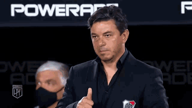 a man in a suit and tie is giving a thumbs up sign .