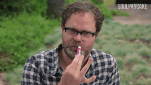 a man in a plaid shirt is applying lip balm to his lips .
