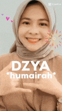 a woman wearing a hijab is smiling and pointing at herself with the name dzya humairah