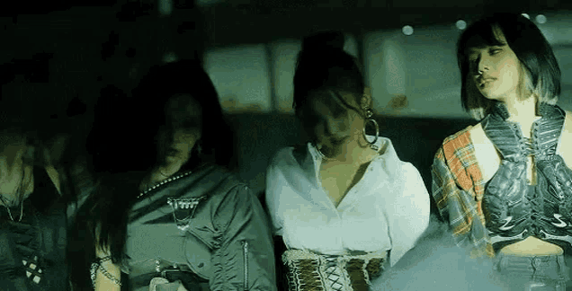 a group of women are standing next to each other in a dark room in a dark room .