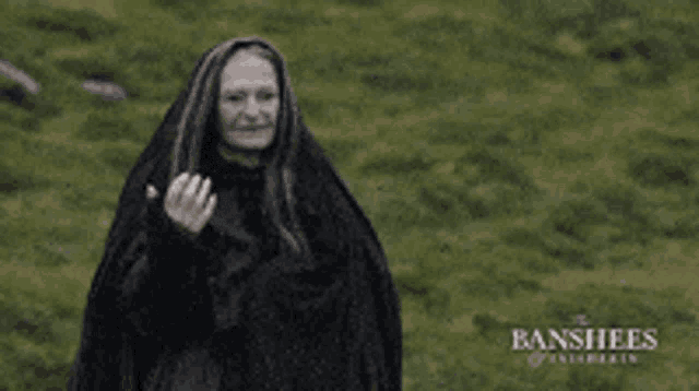 a woman in a black cape is standing in a grassy field