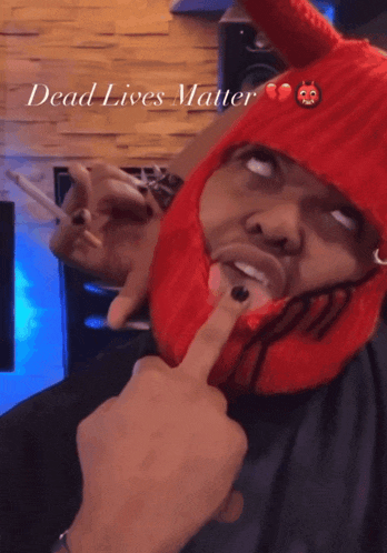 a man wearing a red devil hat is smoking a cigarette with the words dead lives matter above him