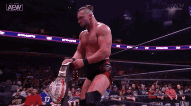 a wrestler is holding a rope in his hands while standing in the ring .