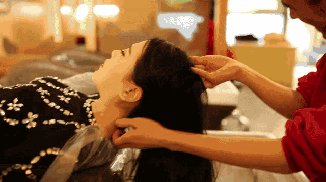 a woman getting her hair dyed by a man in a red shirt