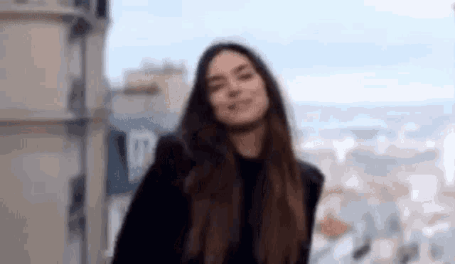 a woman with long hair is standing in front of a building .