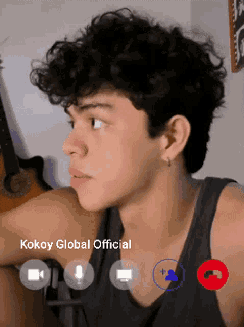 a young man with curly hair is on a video call with kokoy global
