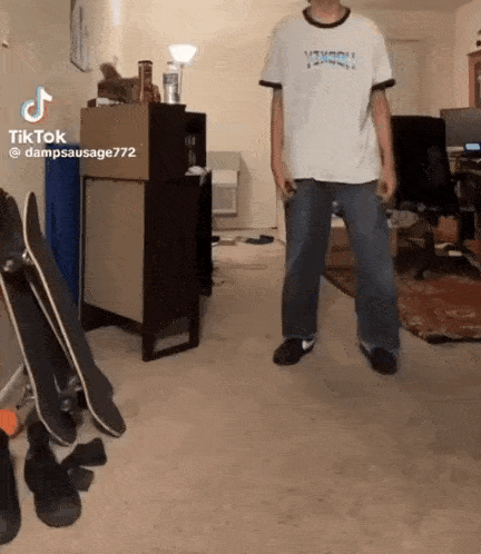 a man is standing in a living room with skateboards .