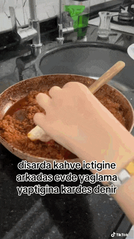 a person is stirring food in a pan with a wooden spoon