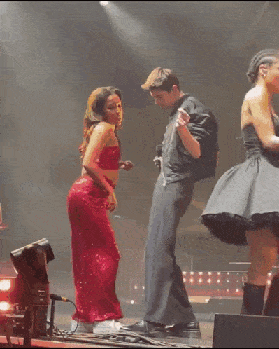 a woman in a red dress sits on a man 's lap on a stage