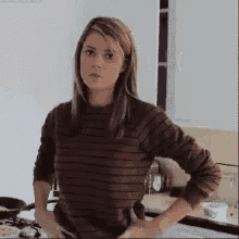 a woman is standing in a kitchen with her hands on her hips