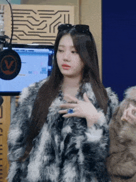 a woman wearing sunglasses and a fur coat is standing in front of a microphone