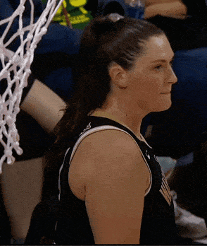 a female basketball player wearing a black jersey with a ponytail on her head