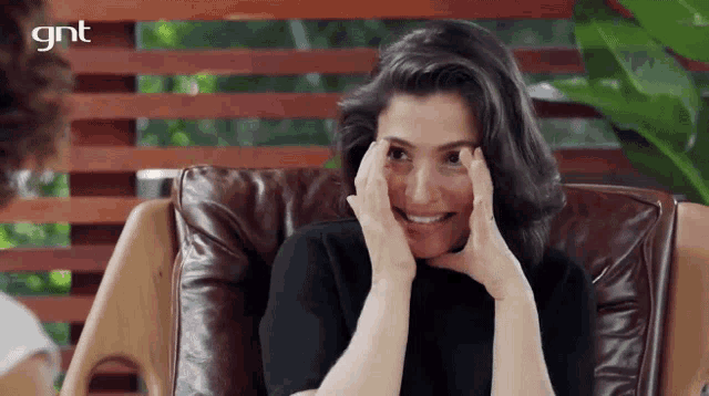 a woman is sitting in a chair with her hands on her face and a gnt logo in the background