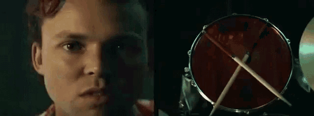 a man with a beard is playing a guitar in a dark room and looking at the camera .