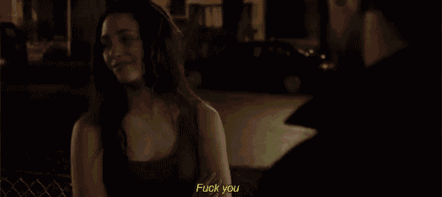 a woman is talking to a man in a dark room and the woman is saying fuck you .