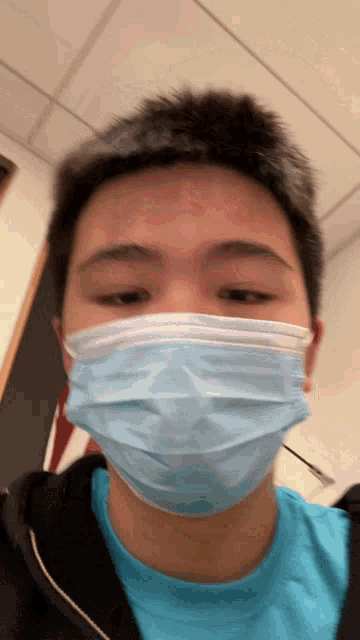 a young man wearing a blue face mask and a black shirt