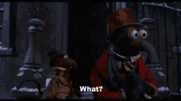 a muppet in a top hat talks to another muppet in a red coat