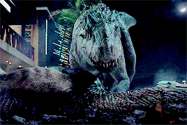 a t-rex is standing on top of a pile of rocks in a city at night