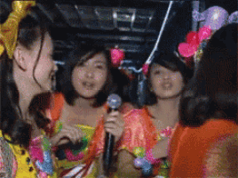 a girl holding a microphone in front of a group of girls