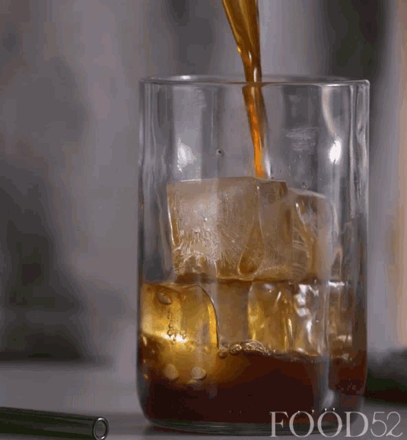 a glass of iced tea is being poured into a glass with food52 written on the bottom