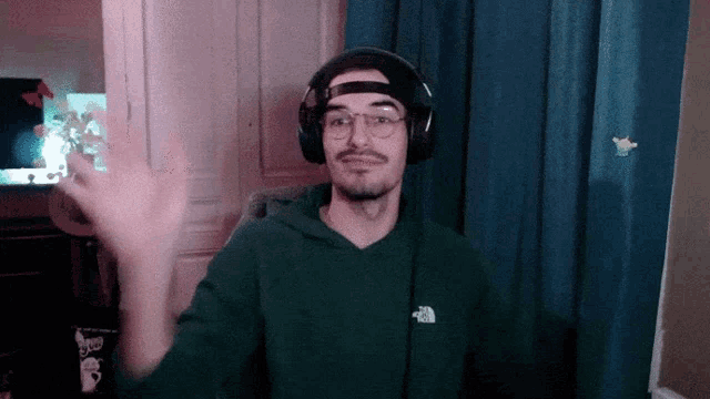 a man wearing headphones and a green hoodie with the north face logo on it