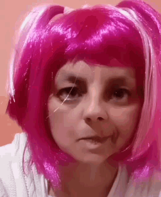 a woman wearing a pink wig with pigtails is making a face .