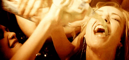 a woman is drinking from a bottle while another woman laughs .