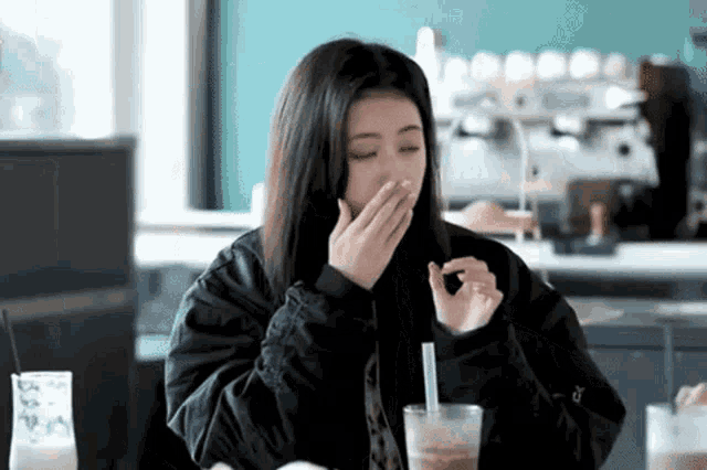 a woman is sitting at a table eating a snack and drinking a smoothie .