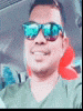 a man wearing sunglasses and a green shirt is smiling while sitting in a car .