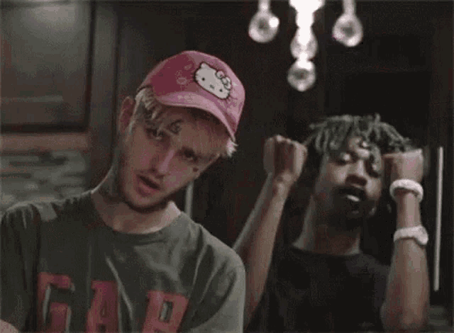 a man wearing a pink hello kitty hat and a green shirt is standing next to another man .