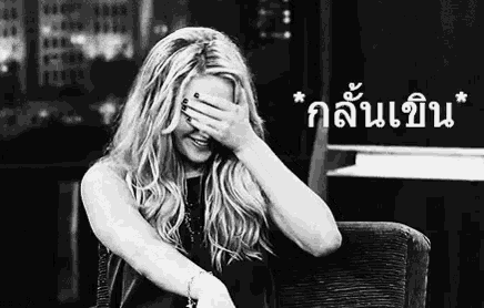 a woman is sitting in a chair covering her face with her hand .