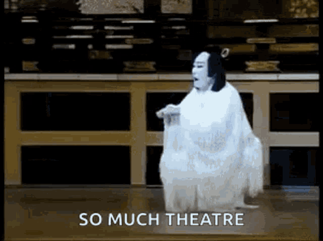a woman in a white dress is dancing in a theatre and the words `` so much theatre '' are written below her .