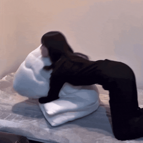 a woman laying on a bed with a white pillow on her back