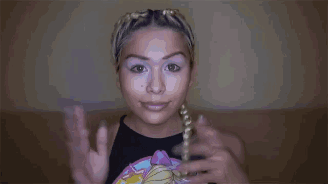 a woman wearing a barbie t-shirt is making a peace sign with her hands .