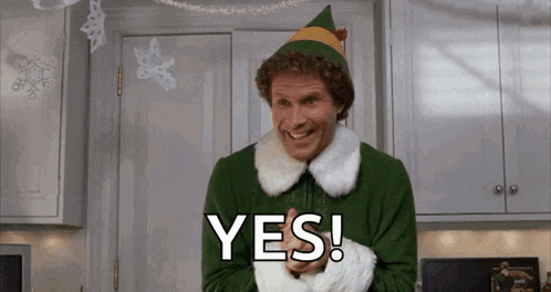 a man dressed as a christmas elf is smiling and saying yes in a kitchen .