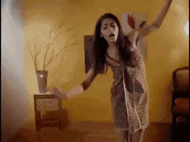 a woman is dancing in a room with her arms outstretched .