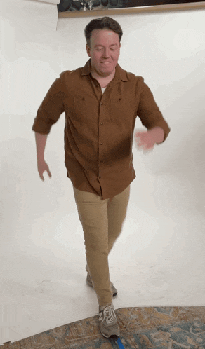 a man wearing a brown shirt and khaki pants is walking