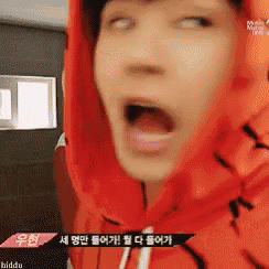 a man wearing a red hoodie is making a funny face with his mouth open