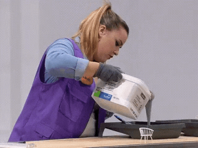 a woman in a purple vest pours a bucket of paint