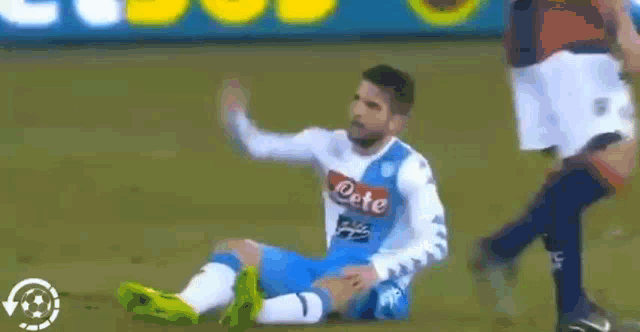 a soccer player in a white shirt and blue shorts is kicking another player in the balls .