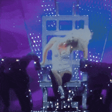 a woman in a white dress is dancing on a stage with purple lights behind her